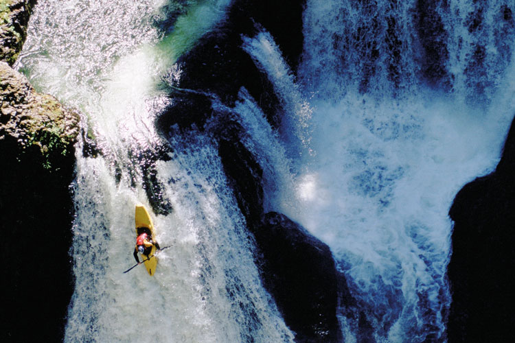 A person taking a canoe down a waterfall