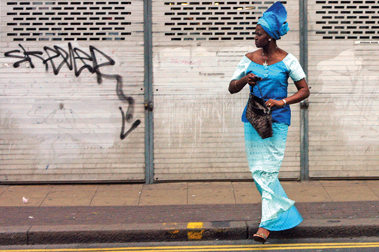 Brightly dressed woman crossing street, Peckham, London