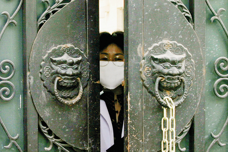 Woman wearing face mask peeps through door