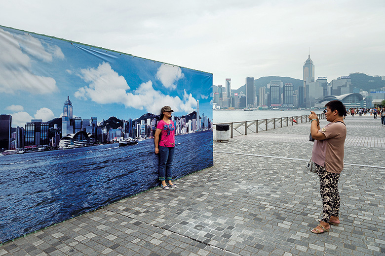 Girl taking photo against Hong Kong city skyline backdrop