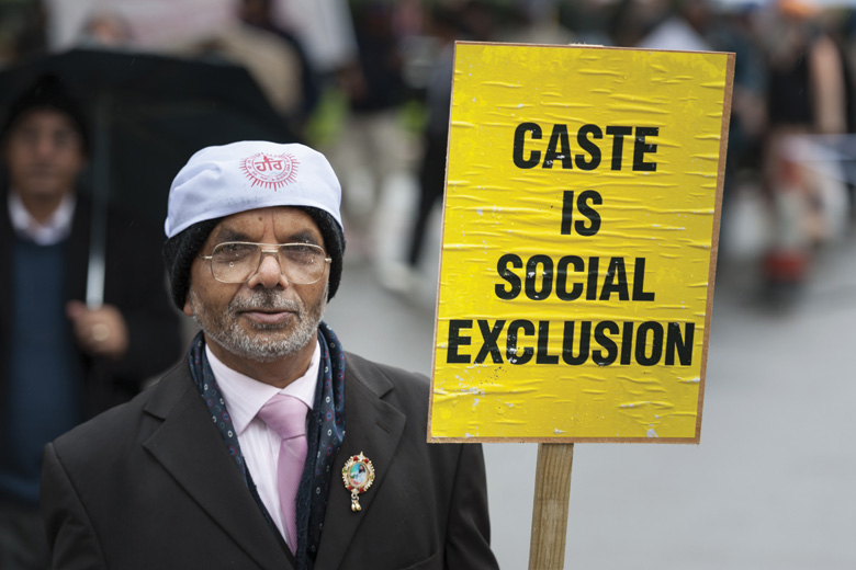 Man holding 'Caste is social exclusion' sign