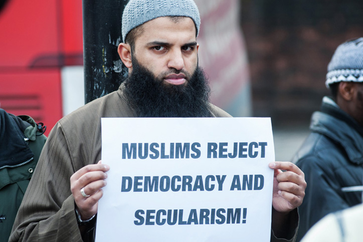 Man holding 'Muslims reject democracy and secularism' sign