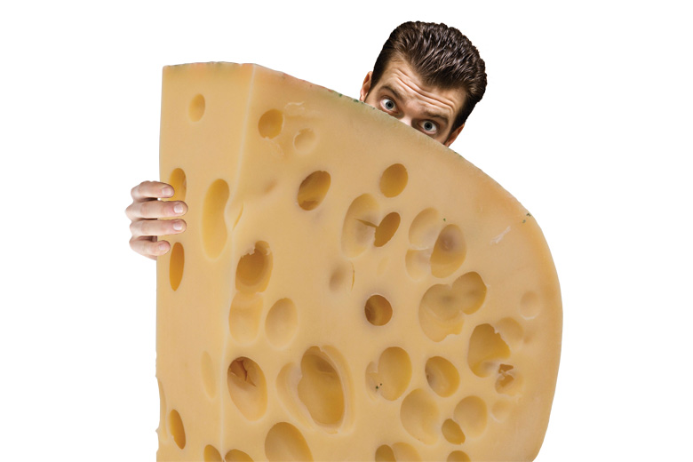 Man peeking from behind piece of swiss cheese