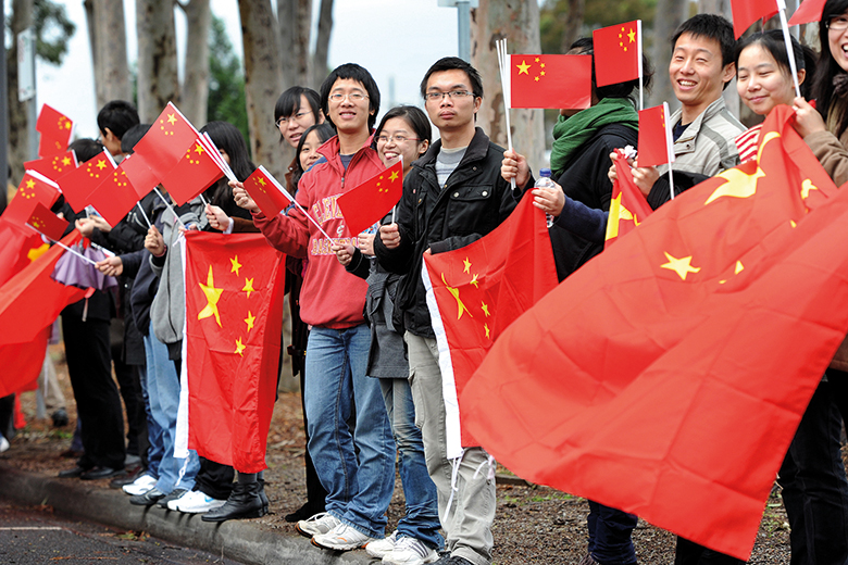 Chinese consular staff wave national flags in front of a demonstration by supporters of the Falun Gong spiritual movement outside the venue where Xi Jinping opened Australia’s first Chinese Medicine Confucius Institute, in 2010. 