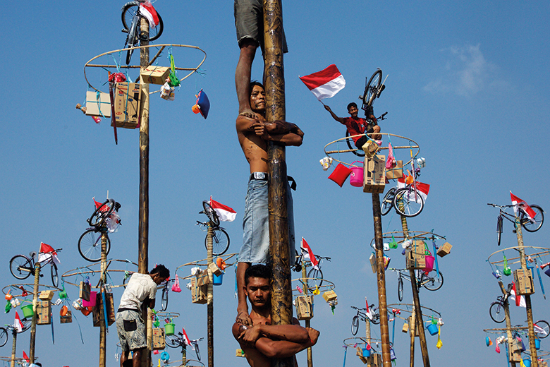 Men climb poles during Panjat-Pinang in Indonesia