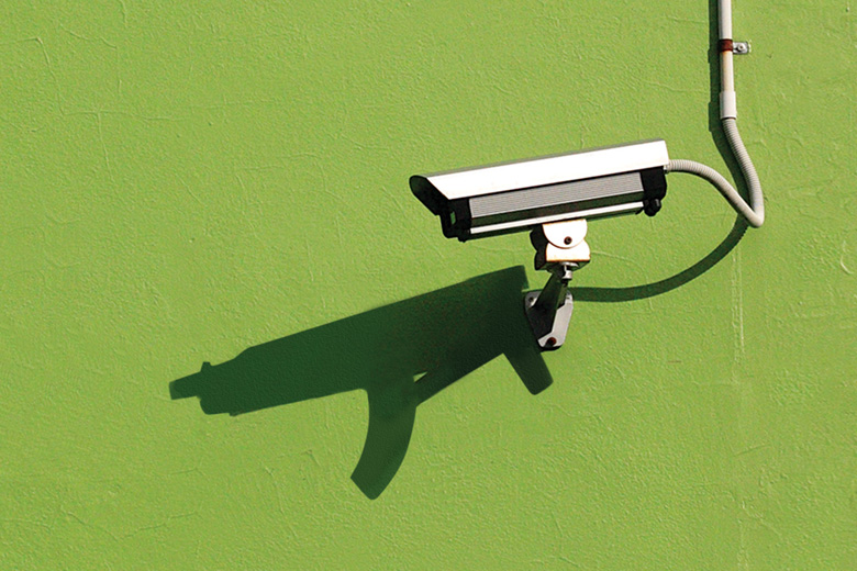 Mounted CCTV camera casting shadow of automatic weapon