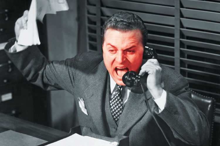 Red-faced businessman shouting into telephone