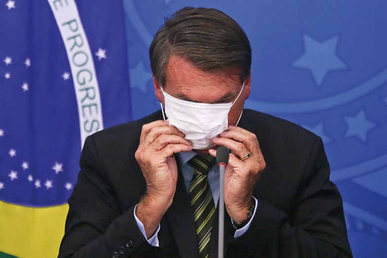 President of Brazil Jair Bolsonaro adjusts his protective mask during a press conference in March 2020