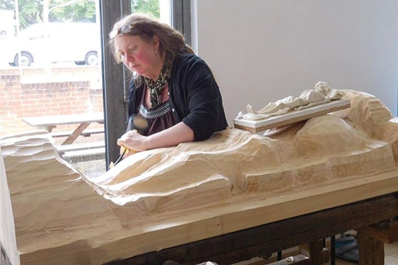 Carving a wooden figure of a corpse