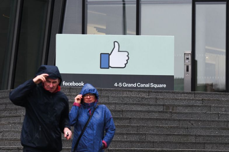 People pass in front of European HQ of Facebook
