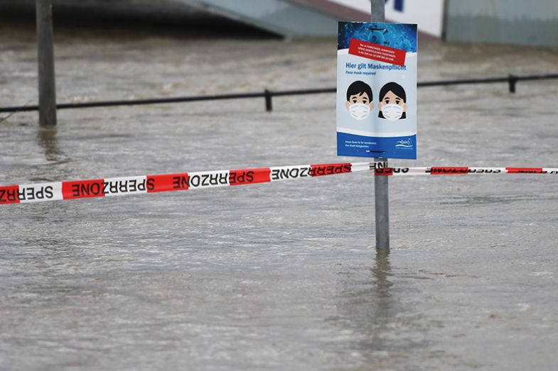 A sign for the compulsory wearing of face masks during the coronavirus pandemic is seen on the banks of the flooded Rhine river in Koenigswinter, western Germany, on February 3, 2021 