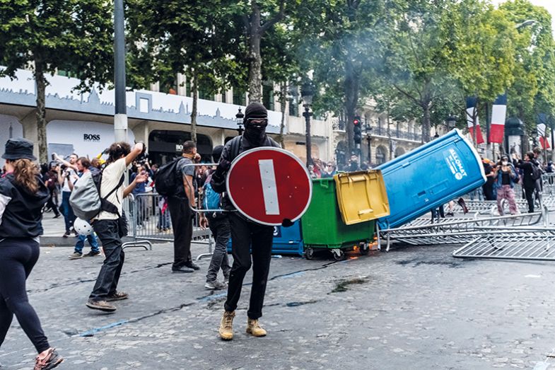 A demonstrator holds a STOP sign as a shield during gilets jaunes protests on the Champs-Elysees