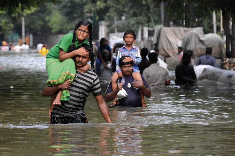 Indian residents carry children as they walk through floodwaters in Chennai on December 3, 2015