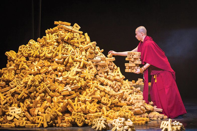 A Buddhist monk stacks models of Chinese characters from a large pile