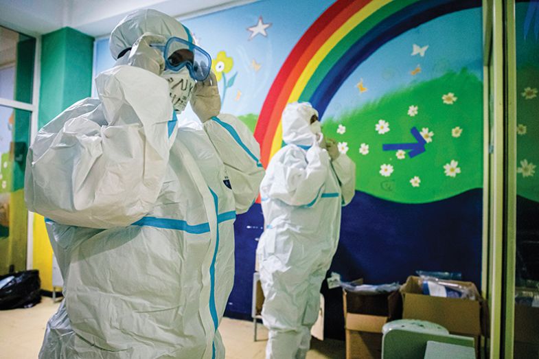 People in PPE in front of a rainbow mural
