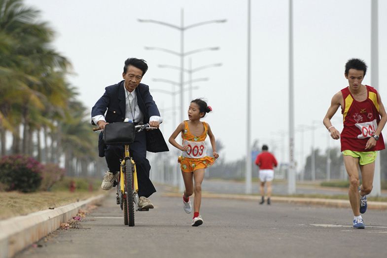 girl runs beside man on bike