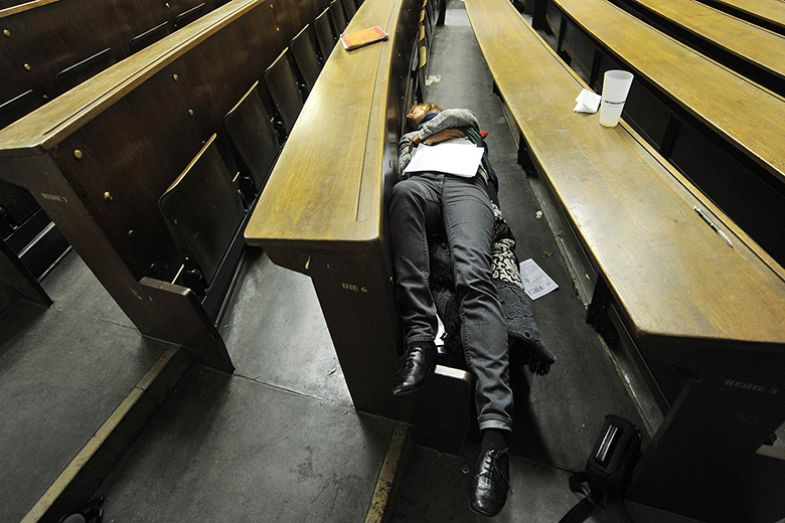 Student asleep in a lecture hall illustrating analysis of status of postdoctoral researchers