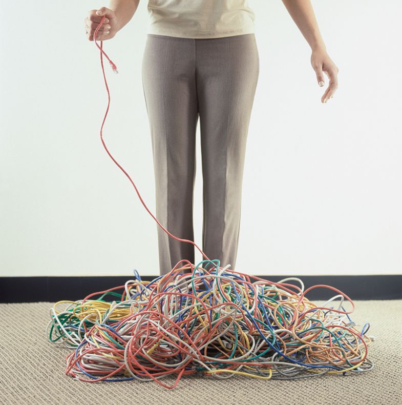 Woman holding a wire coming from a pile of wires on the floor