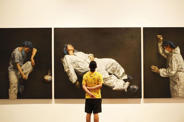 Visitor looks at art exhibition on coronavirus prevention and control at Sichuan Fine Arts Institute in Chognqing, China