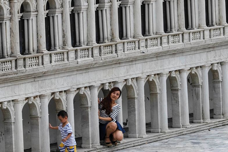 A woman poses near the Venetian Saint Mark's Square miniature in the theme park "Window Of The World" in Shenzhen, Guangdong province, China, October 20, 2014