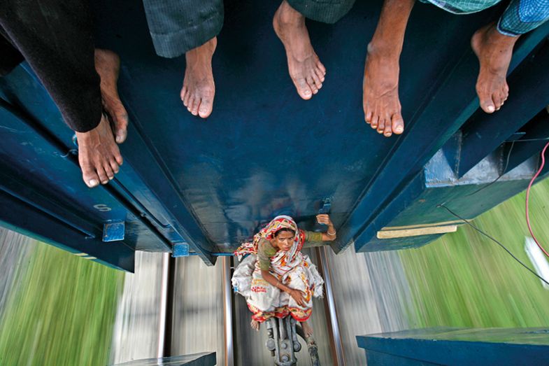 A woman sits between carriages as the train travels to Mymensing from Dhaka September 20, 2009.