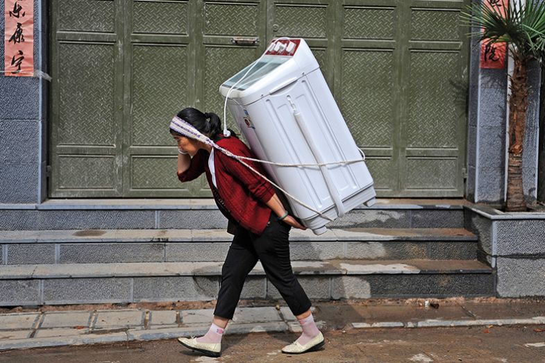 A woman carries home a washing machine in Dali, Yunnan province July 30, 2013.