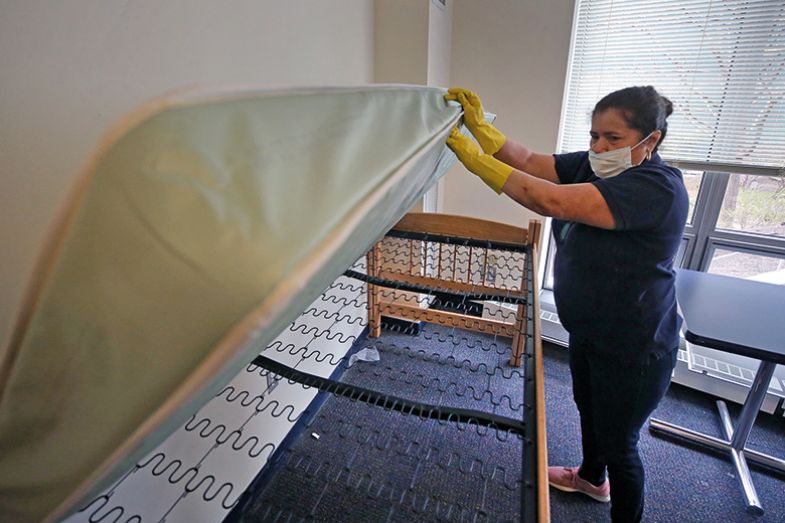 A cleaning company employee inspects a bed in a dorm unit of a university during the coronavirus pandemic