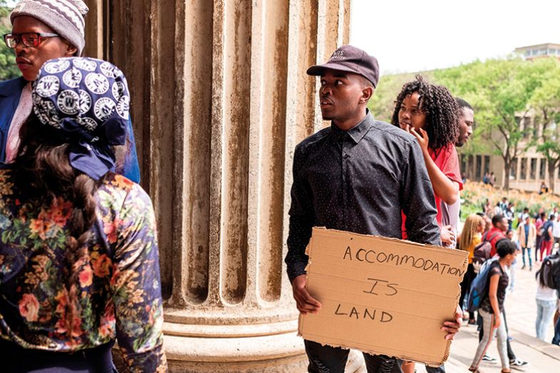 A student holds a placard that reads "Accommodation is Land" on the WITS University Campus in Johannesburg's central suburb of Braamfontein