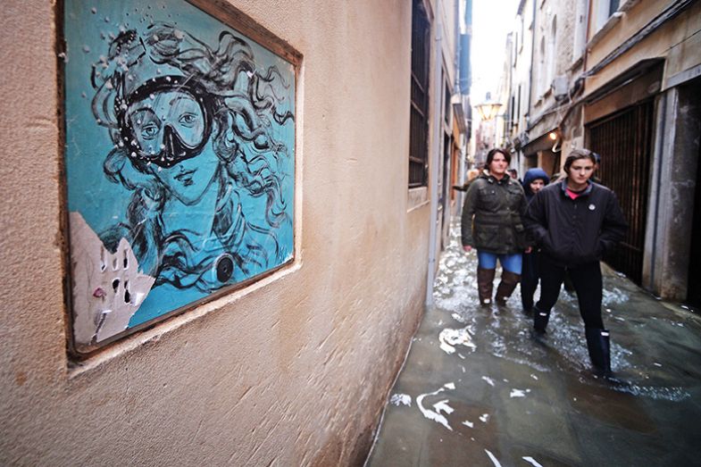 People walk in a flooded street in Venice, during “acqua alta”, or high water, of 160 centimetres (over five feet), on November 17, 2019