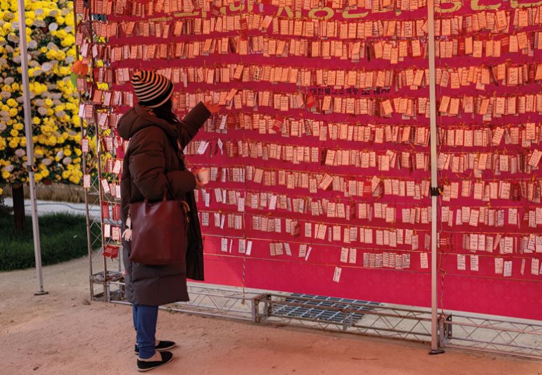 A woman hangs a note to wish for her child's success in the College Scholastic Ability Test at Chogey buddhist temple