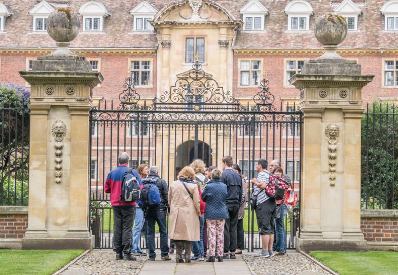 A group of tourists stand outside the gated entrance to St Catherine's college, university of Cambridge, England to illustrate it being closed for admissions