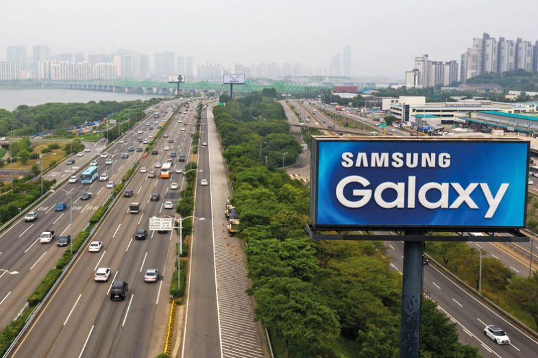 An advertisement for Samsung Electronics Co. Galaxy smartphones stands next to vehicles traveling along the road in an aerial photograph taken in Seoul, South Korea