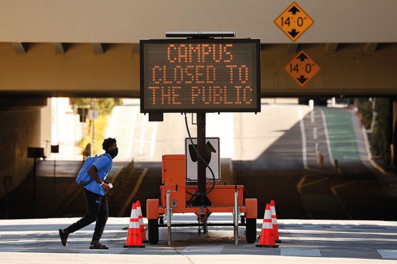 Person walks past Campus Closed to public sign.