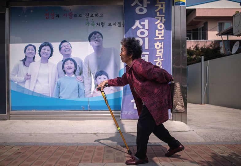 An elderly woman walks past a poster at a health centre in Gunwi