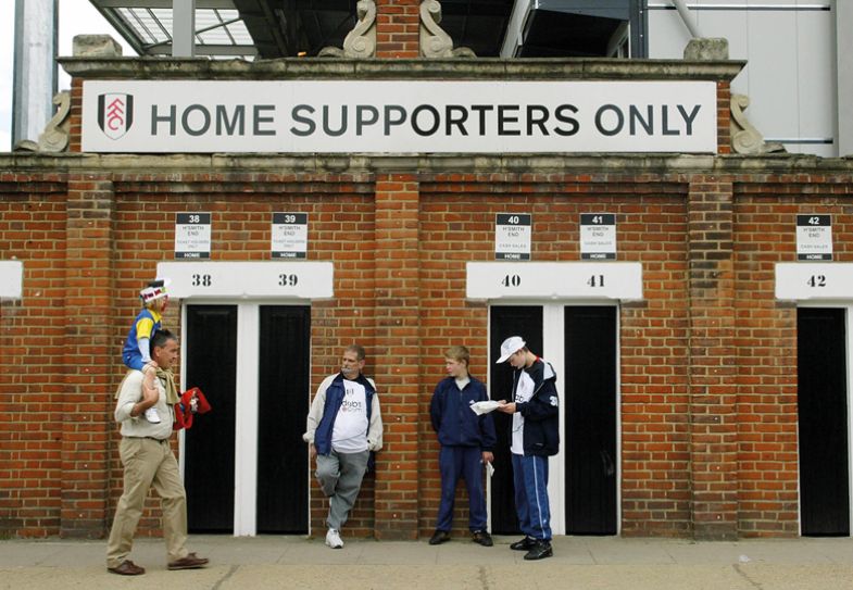 Fulham football club supporters wait outside the turnstiles