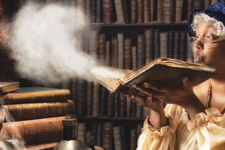 Medieval alchemist blowing dust off an old book