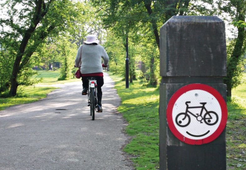 A cyclist ignores the no cycling sign which has a smile edited