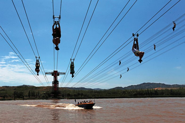 Tourists slide on the cableways across the Yellow River, China