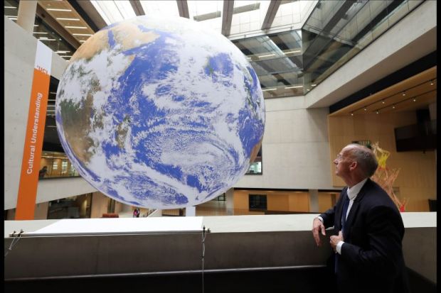 A man looks at a giant globe