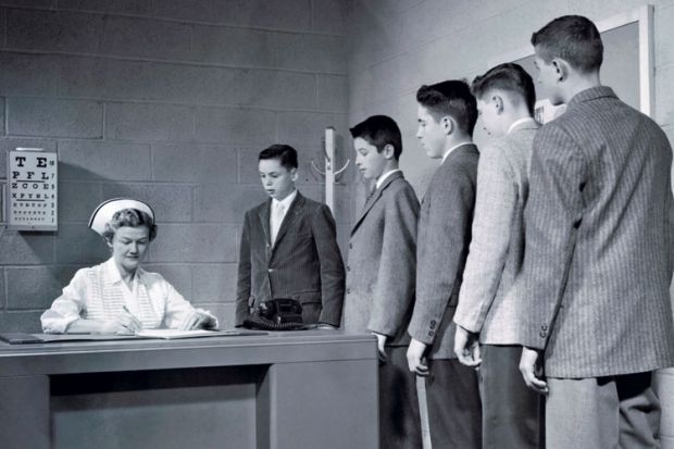 A nurse sitting at a table with a queue of people waiting to speak to her