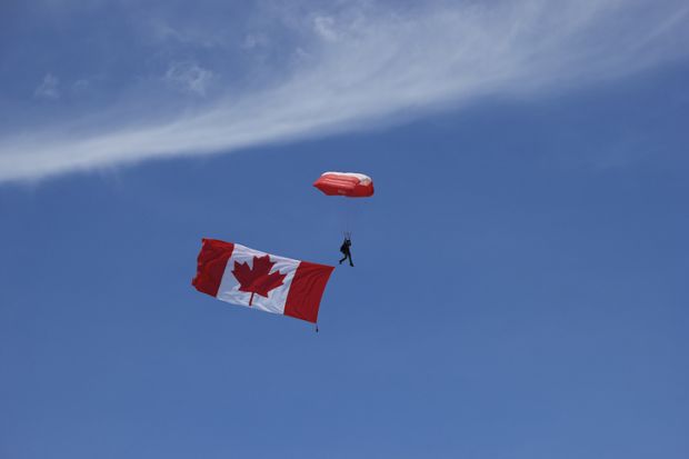 A Skyhawk team member is seen in the image with the flag of Canada, The Maple Leaf in tow at the beginning of the performance at the 2016 Duluth Air Show