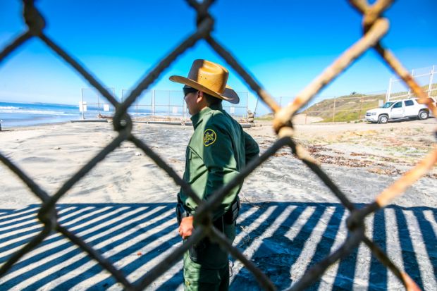 An agent of the US Border Patrol inspects the steel wall on the border between the United States and Mexico build on the Pacific coast of Tijuana