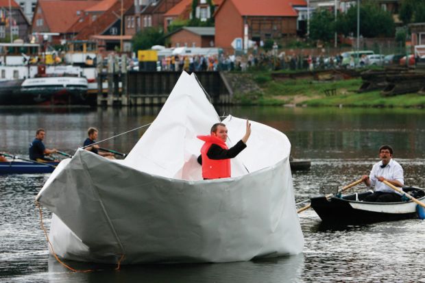Artist Frank Boelter sitting in life-size paper boat