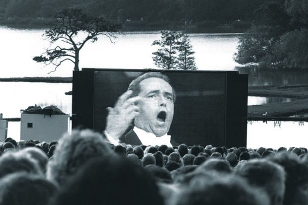 Audience watching opera singer on large screen