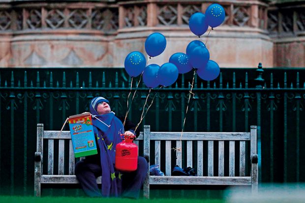 An anti-Brexit activist holds EU-flag-themed balloons outside of the Houses of Parliament in 2019 illustrating rise in university fees for EU students in England