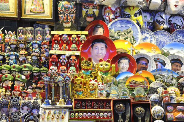 Beijing, China - October 19, 2014 - A souvenir stall at a Beijing night market selling Xi Jinping face plates and other kitsch