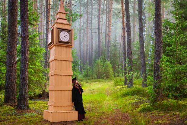 Graduate leaning on model of Big Ben in forest