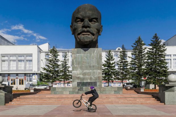 Boy riding BMX in front of bust of Vladimir Lenin