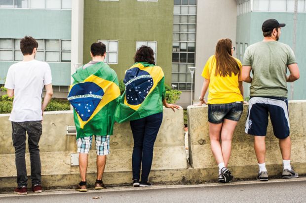 Brazilians with flags looking over wall