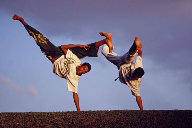 Brazilian men performing capoeira outdoors